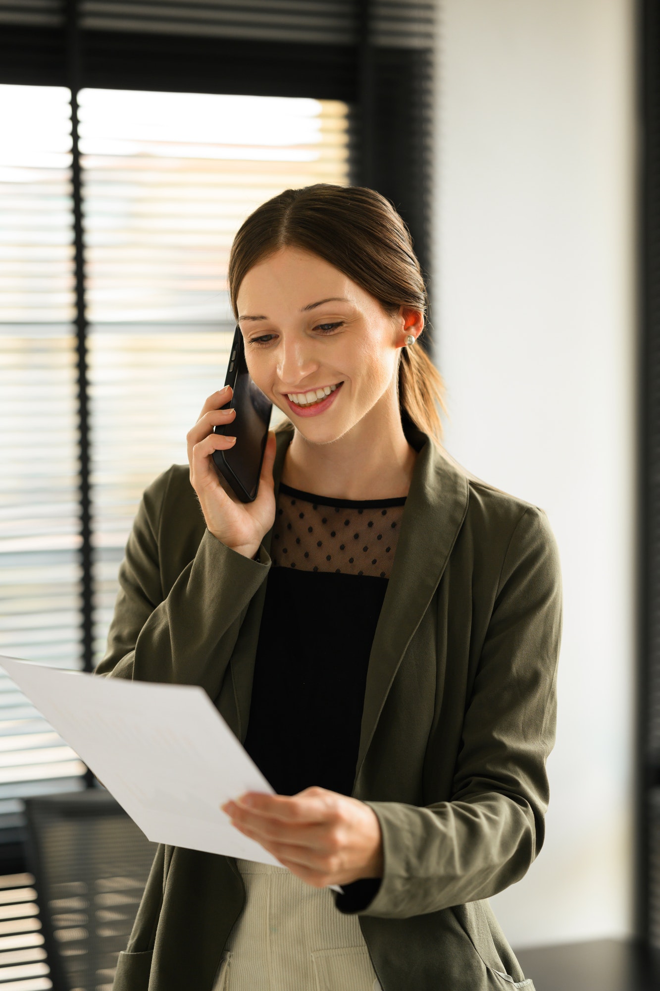 Attractive female financial consultant chatting with client on mobile phone.
